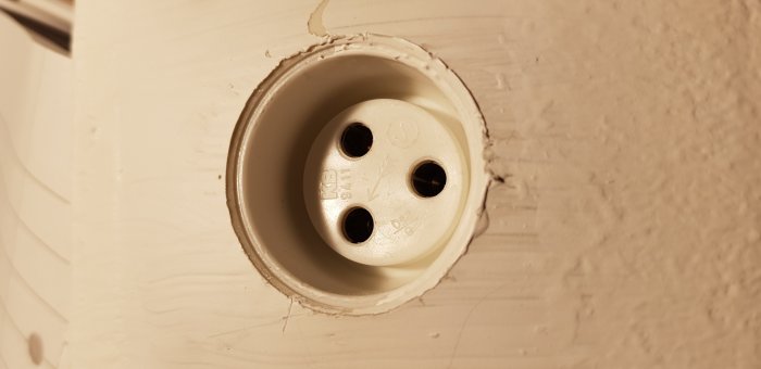 Ett äldre tretakts takuttag i vitt på en målad vägg.
