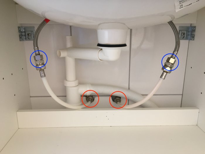 Tvättställsavlopp och vattenslangar under diskbänk, markerade med röda och blåa ringar där ändringar föreslås.