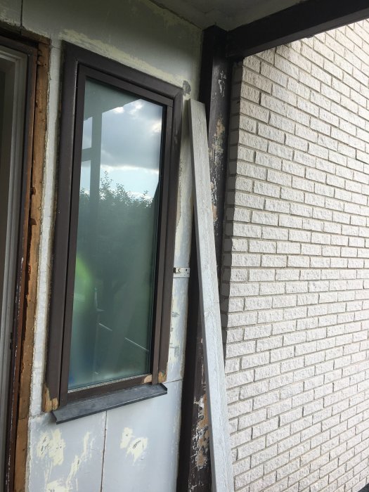 Fönsterområde under renovering med synlig fukt- och mögelskada på masonit och trä.