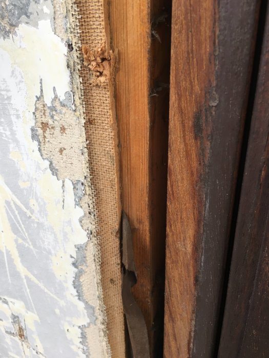 Skadad masonit och fuktigt trä längst ner på en vägg intill klinkers och en tröskel.