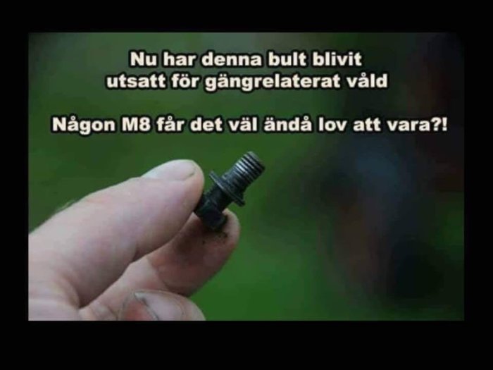 Hand håller en skadad bult med text som skämtar om gängrelaterat våld på bulten.