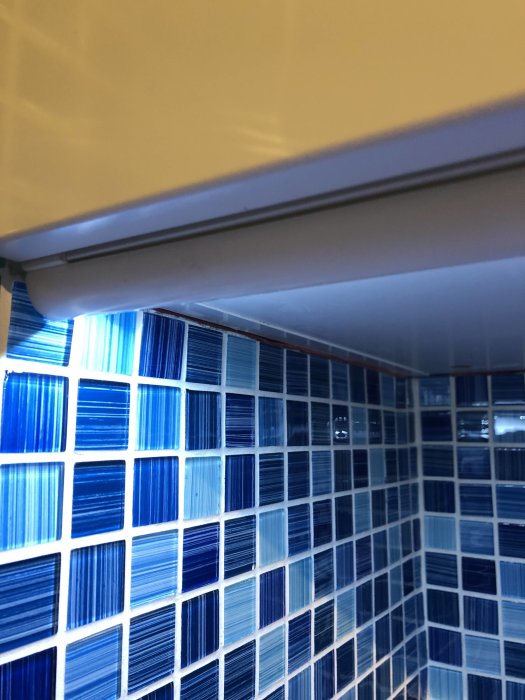 Plastkakellist monterad ovanför blått kakel i en tvättstuga.