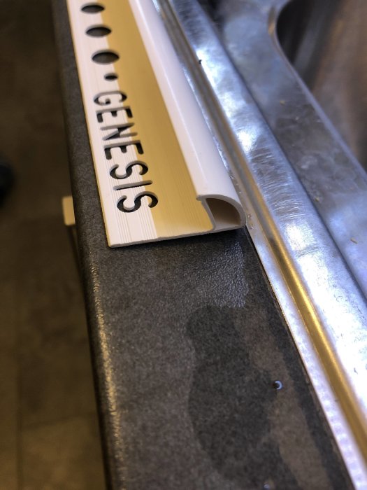 Plastkakellist märkt "GENESIS" vid kanten av en tvättstuga bänkskiva.