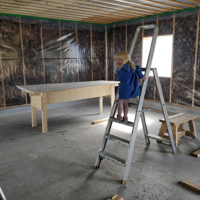 Barn hjälper till i verkstad med isolerade väggar och nybyggd arbetsbänk.
