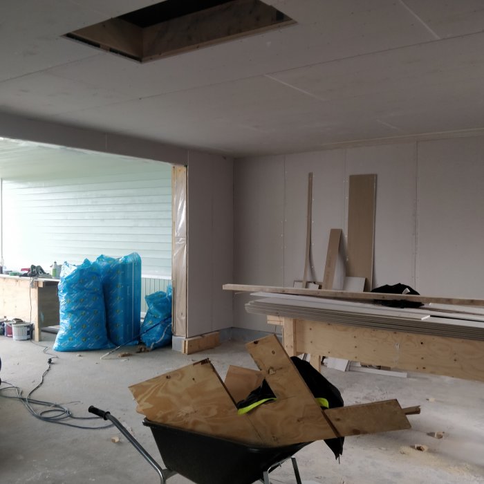 Inredd verkstad med isolerade väggar och gipsade tak, plywood på golvet och en skottkärra med virke.