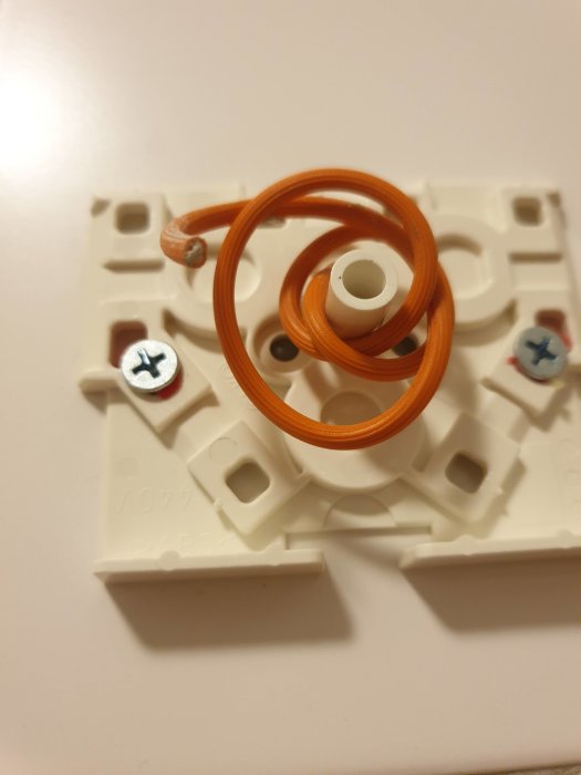 Orangespiral i vit plastdosa, möjligen icke-ansluten installationskabel.