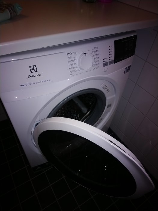 Vit Electrolux tvätt-torkmaskin PerfectCare 700 öppen i ett badrum.