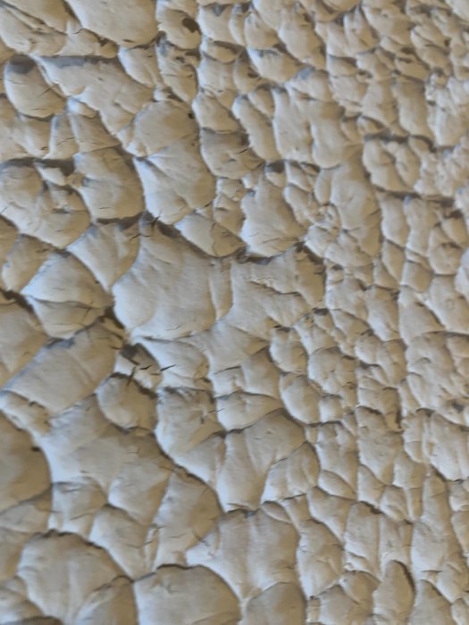 Texturerad kalkputs med struktur som liknar ett stormigt hav på källarvägg.