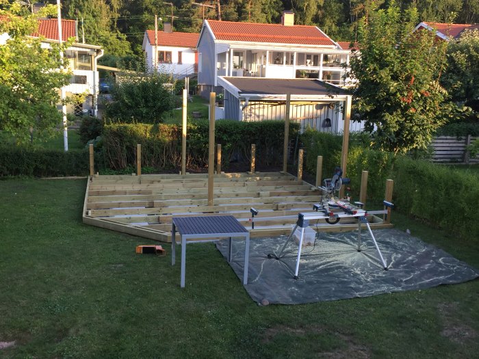 Nybyggd träpergola med markisduk och byggverktyg på en gräsmatta.