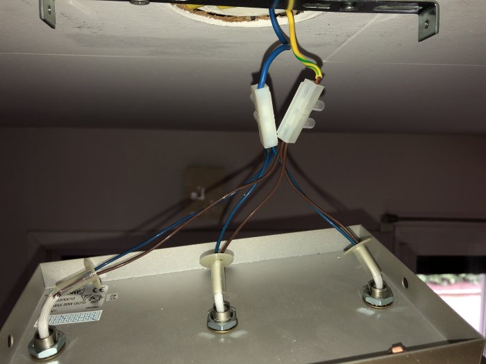 Öppen elektrisk anslutning med blå och brun kablar kopplade via skarvdon, och ett löst gult/grönt.