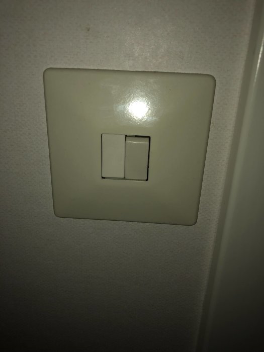 Dubbel ljusströmbrytare på en vägg, högra strömbrytaren kontrollerar två lampor.