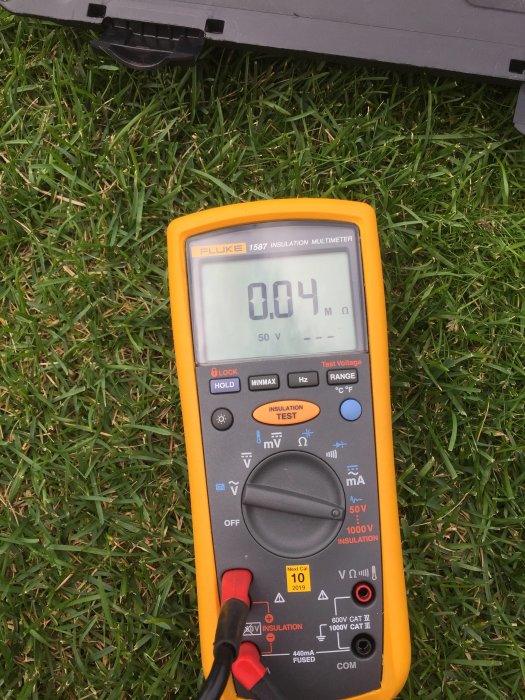 Isolationsmultimeter som visar 0.04 M ohm mot jord på en gräsmatta.