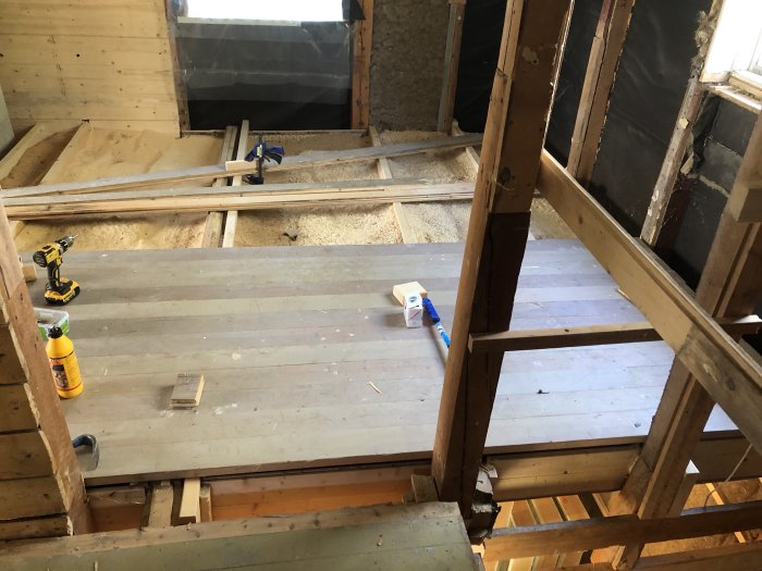 Renovering av övervåning med delvis installerat trägolv, bjälklag och verktyg.
