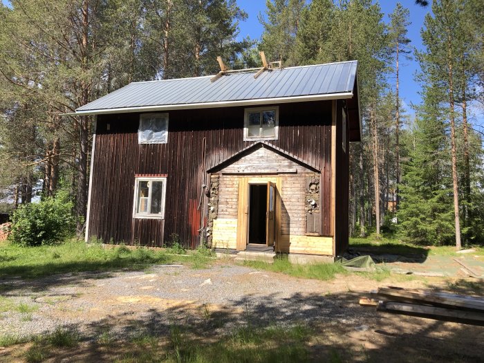 Trähus med omonterade hängrännor och obruten ställning inför målning och installation av nya fönster.