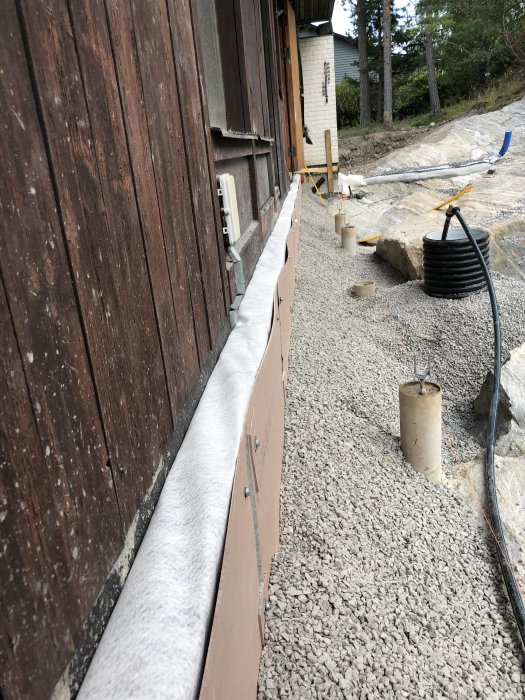Nyinstallerade beige fibercementskivor under en träklädd altan som bågnar från grunden på ett byggprojekt.