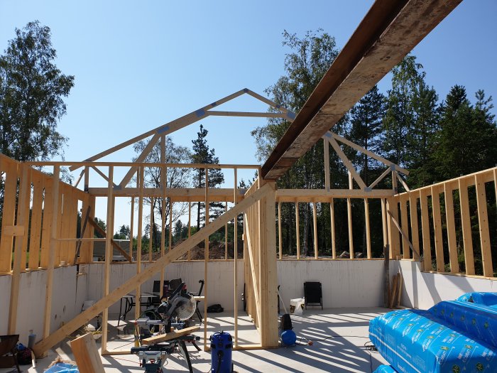 Byggarbetsplats med trästomme för ett hus under konstruktion, verktyg och byggmaterial synliga.