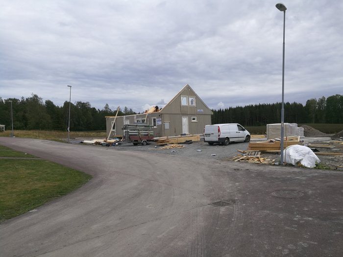 Byggarbetsplats med hus under konstruktion, material och fordon på platsen.