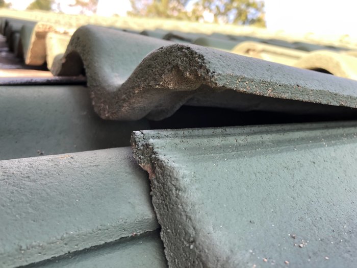 Nahaufnahme eines Daches mit einer Lücke, weil eine Dachpfanne nicht richtig in der Rinne sitzt aufgrund der umgebenden Blechverkleidung.