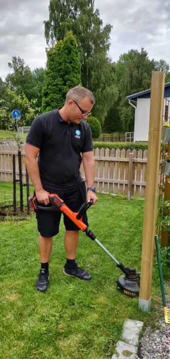 Man som använder en ny tyst grästrimmer i sin trädgård.