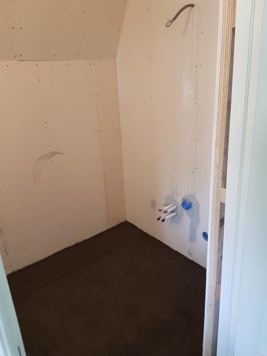 Nyspacklat golv i ett blivande badrum med gipsskivor på väggarna.