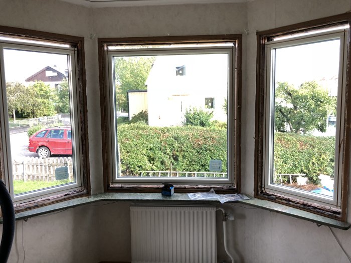 Utsikt från ett orenoverat rum med fyra nyligen utbytta fönster, öppna väggar runt fönsterkarmarna.