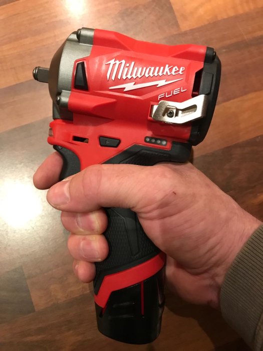 Hand håller en röd och svart Milwaukee FUEL batteridriven slagskruvdragare.