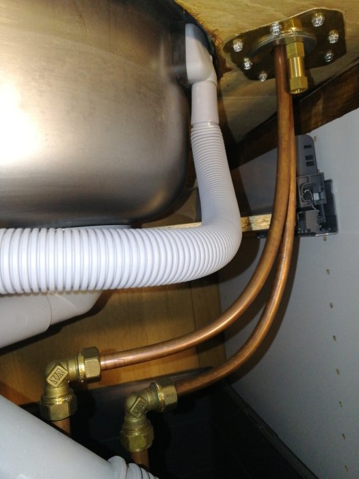 VVS-arrangemang under handfat med kopparledningar och avstängningsventiler.