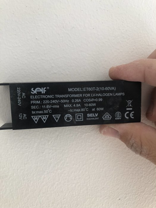 Hand håller en elektronisk transformator för lågvoltshalogenlampor med tekniska specifikationer.