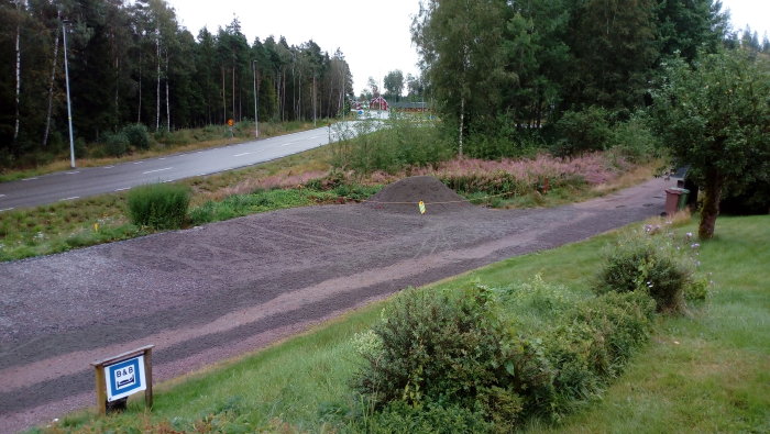 Nygrusade uppfarten med gräsmatta och en skylt för Bed & Breakfast, vid regnigt väder.