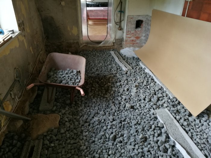 Renovering av skånelänga med borttaget betonggolv och påfyllning av skumglas, markduk synlig.