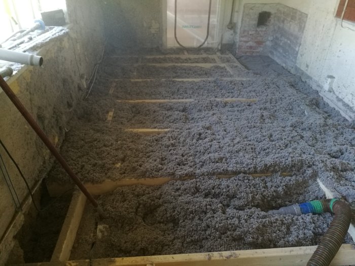 Renoveringsfas av golv med synliga golvreglar och isolering av cellulosafiber i en skånelänga.