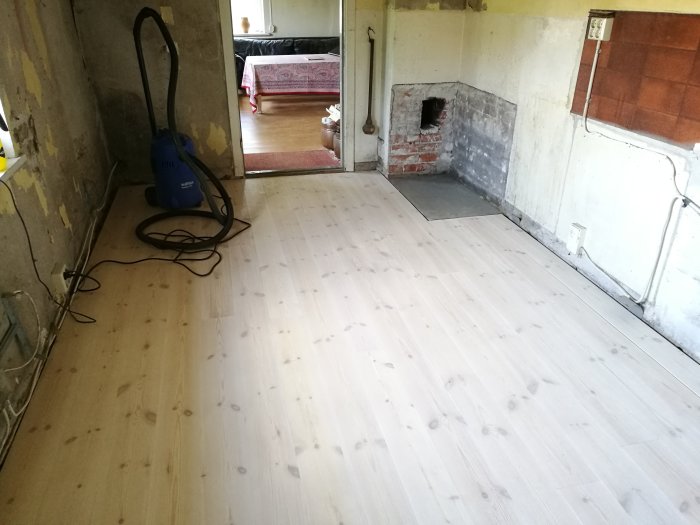 Nyinstallerat trägolv i renoverad skånelänga med synliga golvreglar och isolering.