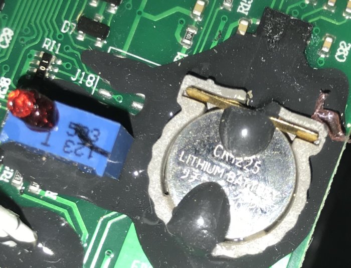 Close-up av ett kretskort med en CR1225 litiumbatteri och närliggande komponenter.
