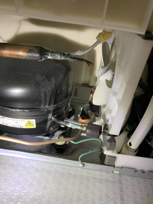 Kompressor och kopplingar med spår av möjlig läckage och smuts i en maskin.