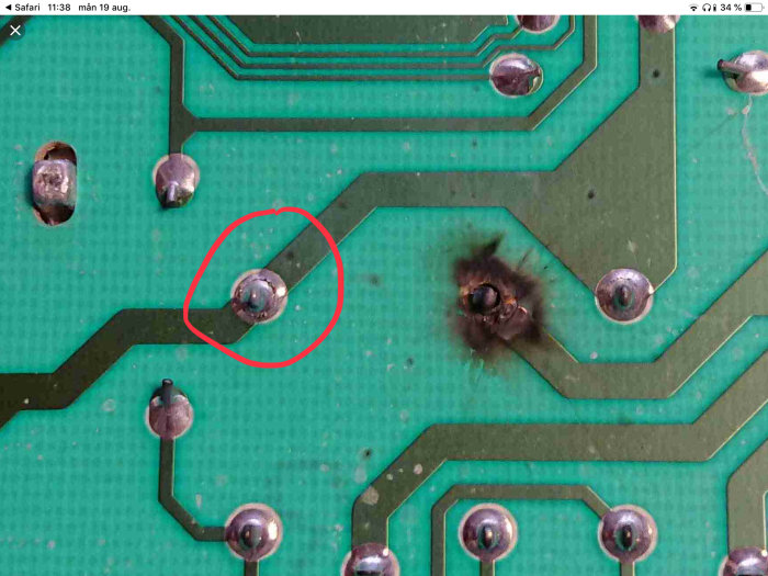 Kretskort med markerad lödpunkt som ser sprucken ut samt en bränd lodpunkt till höger.