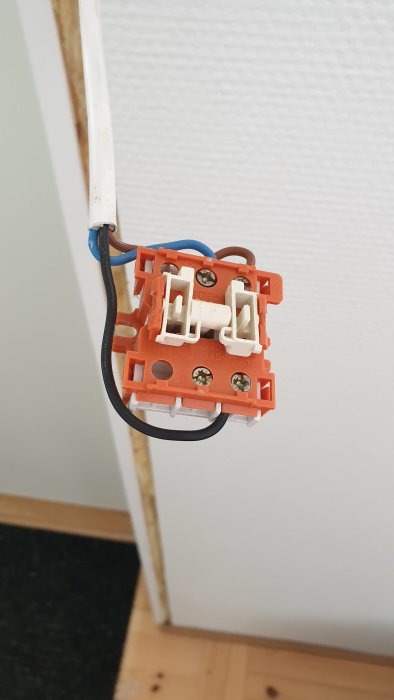 Eluttag med anslutna kablar på en vägg, en vit och en svart ledare syns.