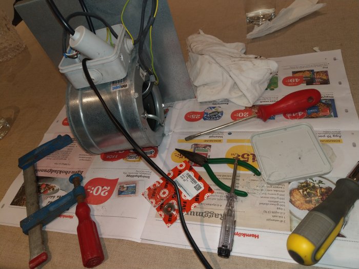 Elektrisk motor och handverktyg utspridda på tidningspapper under lagerbyte.