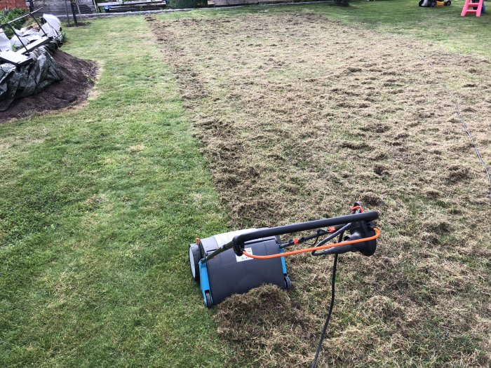 Vertikalskärare på en gräsmatta med nyklippta ränder efter grässkötsel.