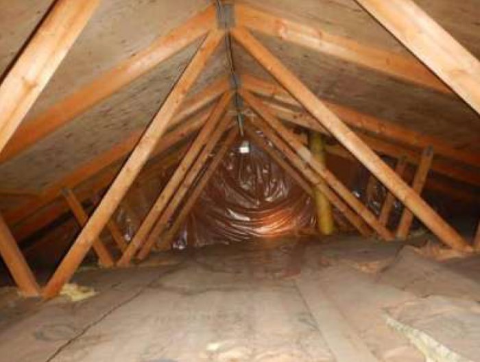 Takstolar i ett husvind med synlig isolering och träkonstruktion, eventuellt icke bärande vägg relaterat.