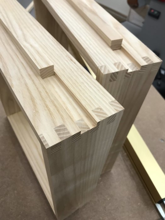 Träkonstruktioner med utförda spår för glidlister som väntar på ytbehandling och montering.