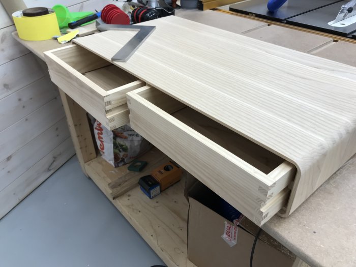 Hantverksmässigt tillverkade trä lådor med glidlister i en verkstad, ytbehandling återstår.