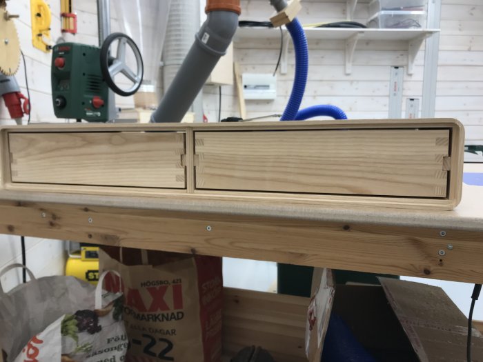 Hemmagjorda trä lådor på arbetsbänk, utan botten och front, med glidlister färdigmonterade.