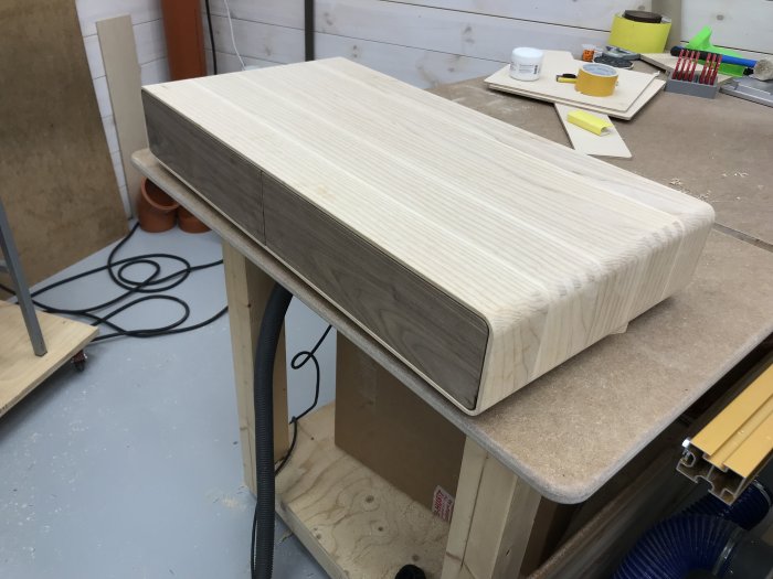 Välpassad träkonstruktion på byggbord med verktyg i bakgrunden.