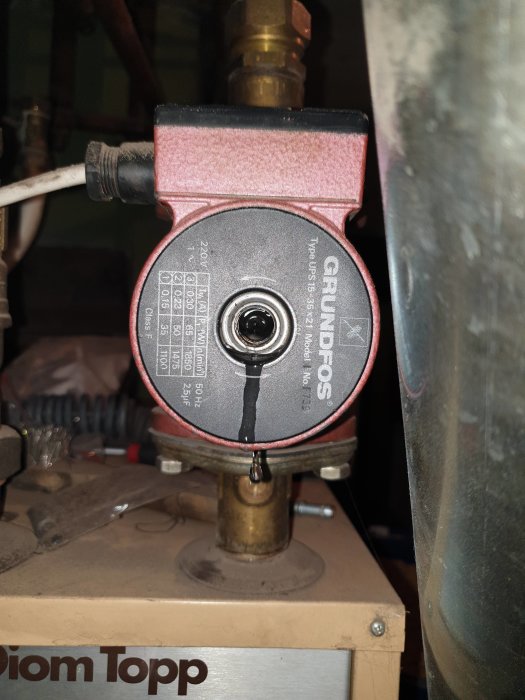 En cirkulationspump från Grundfos monterad på en panna, med tydlig märkning och anslutningsrör.