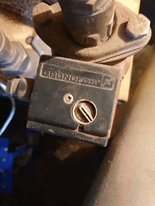 Närbild av en smutsig Grundfos cirkulationspump monterad på en panna.