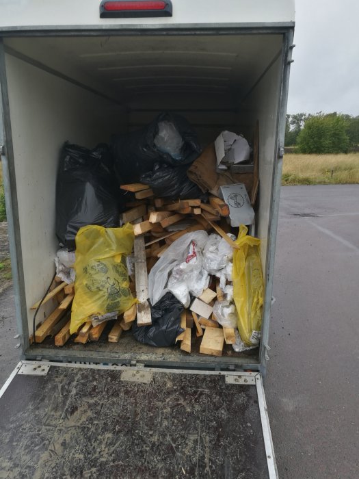 Fullastad släpkärra med byggavfall bestående av trä, plast och kartonger redo för tippen.