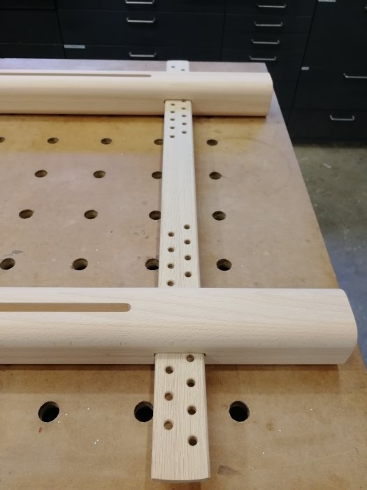 Obehandlade trädelar till en kyrkobroderiram som frästs och borrats ligger på en arbetsbänk.