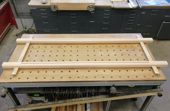 En obehandlad träram av bok och ek utformad för att spänna upp textilier, placerad på ett snickeribord.