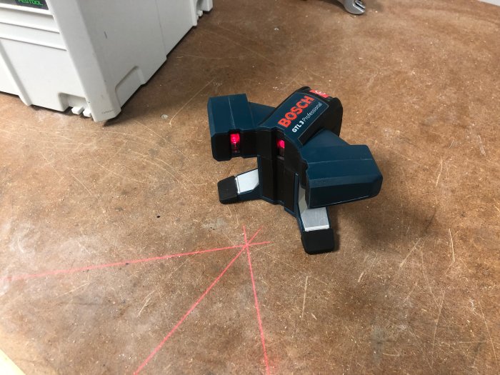 Bosch laserverktyg för kakelläggning med 45/90 graders linjer projicerade på golv.