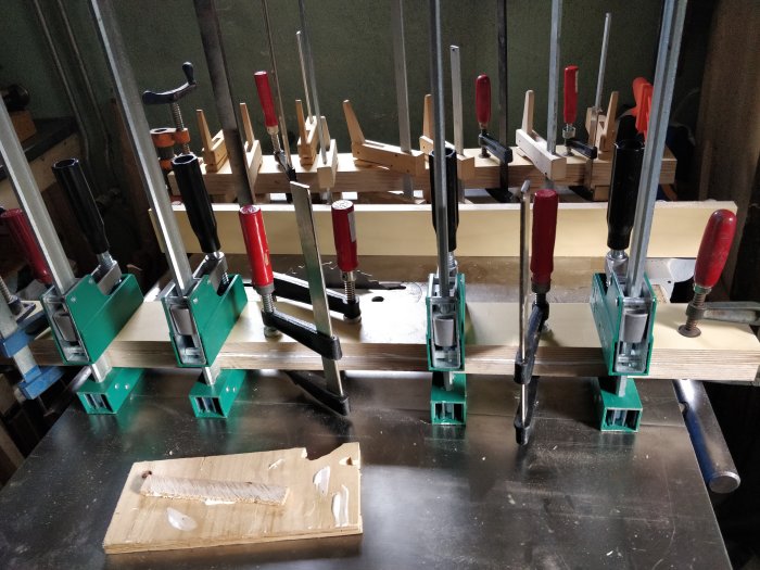 Verktygsbänk med flera olika skruvstycken som håller fast träbitar.